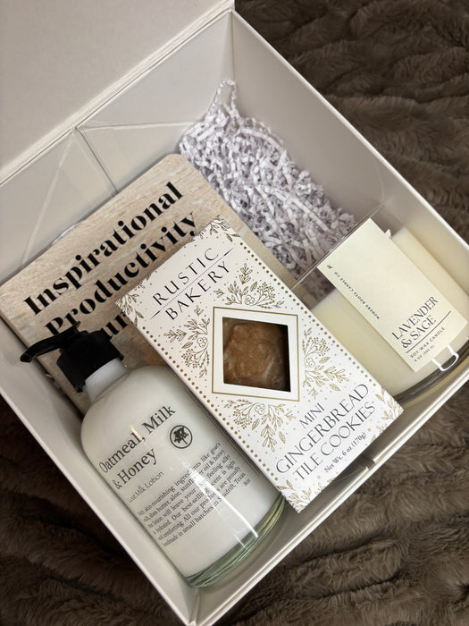 Gift set with skincare products and a book inside a box on a textured surface. Rest & Recharge.